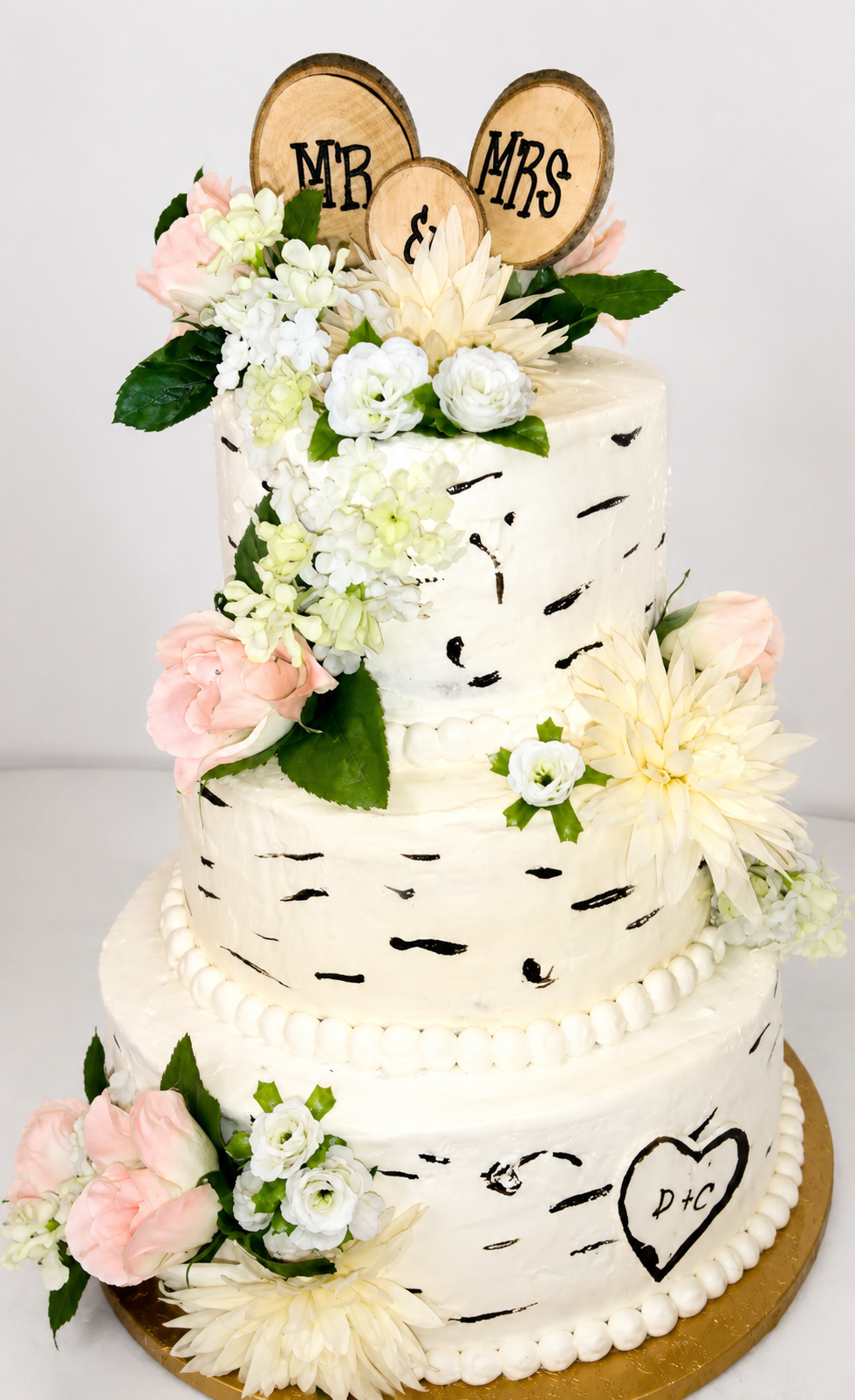 Three-tier white wedding cake with pastel flowers and Mr and Mrs toppers