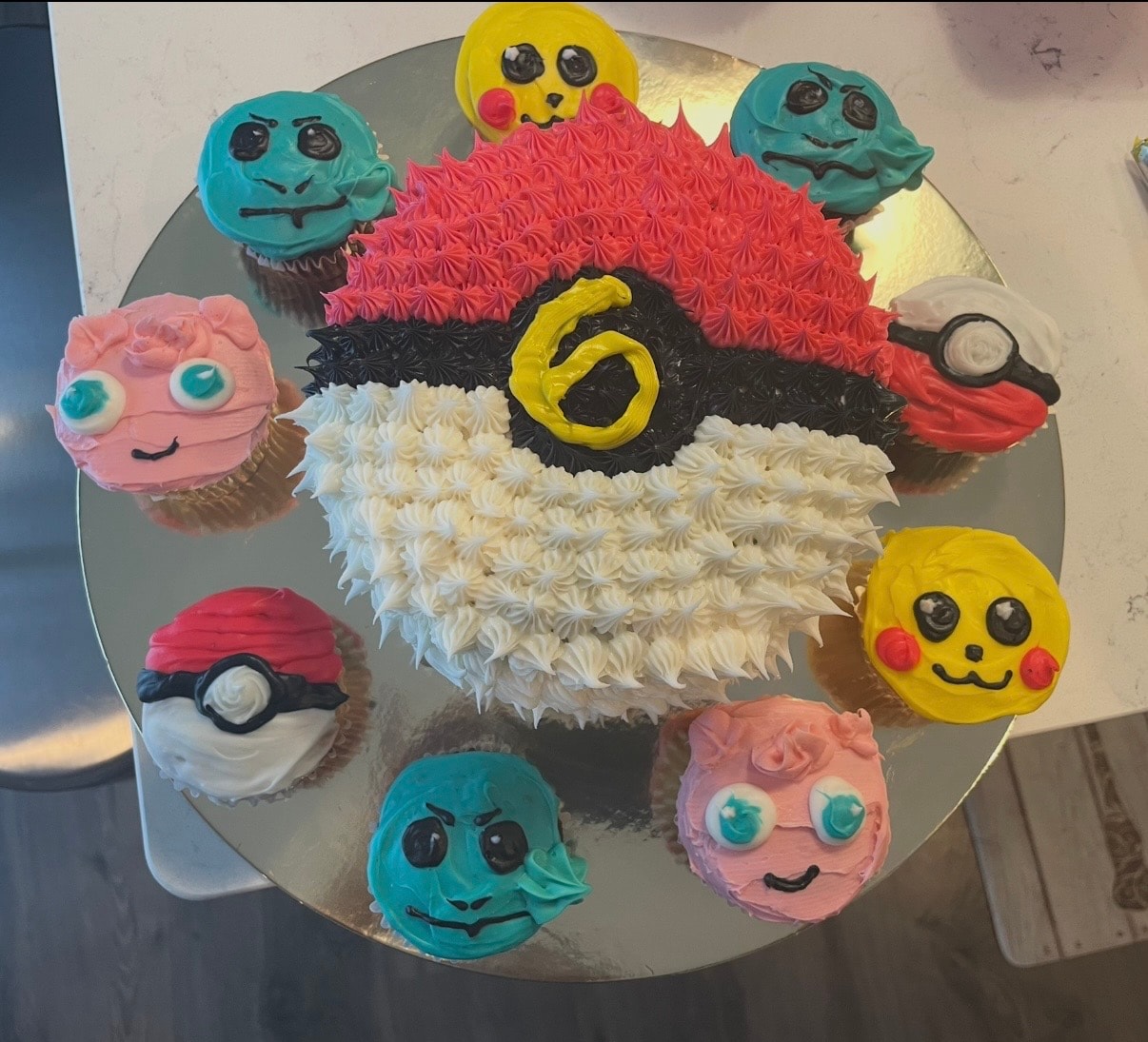 Pokémon-themed pull-apart cupcake cake with Pikachu, Squirtle, and Jigglypuff character cupcakes surrounding a Poké Ball cake for a 6th birthday